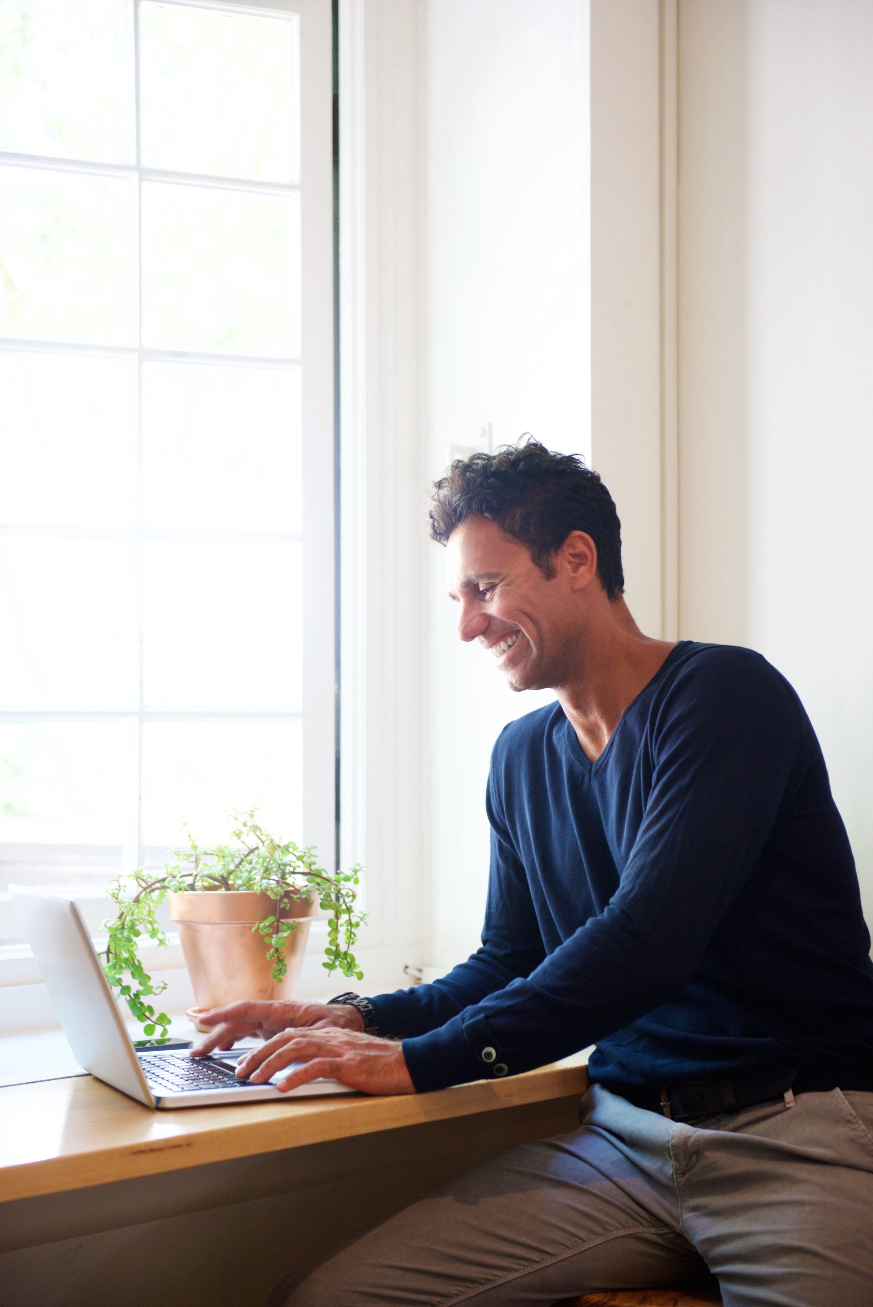 Portrait of a smiling man using laptop at home